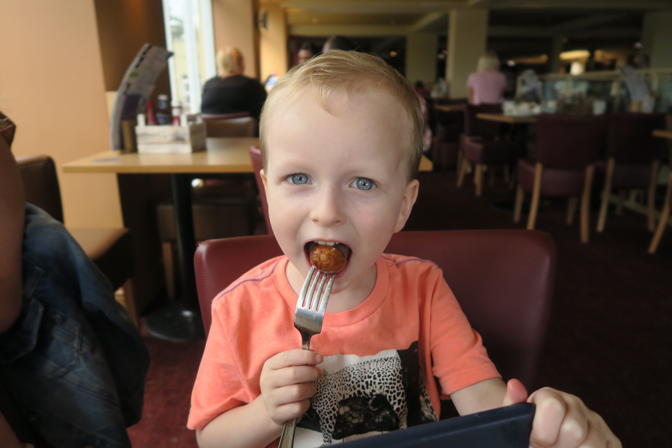 a little boy eating a sausage at the Mash and Barrell pub at Haggerston Castle 