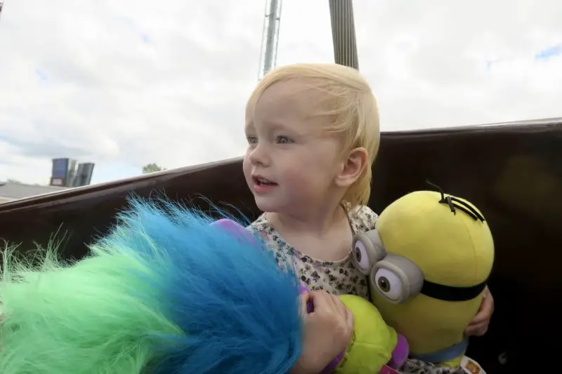 A toddler holding a trolls and minions stuffy that we won from the Flamingo Land grabbers