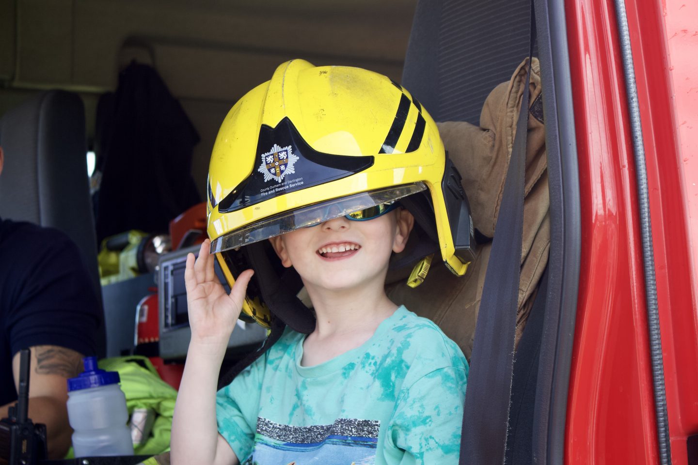 Boy wearing a fireman's hat in a fire truck