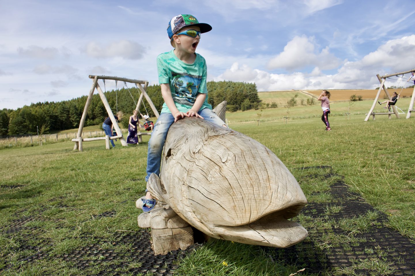 A young boy pretending to ride a large wooden whale