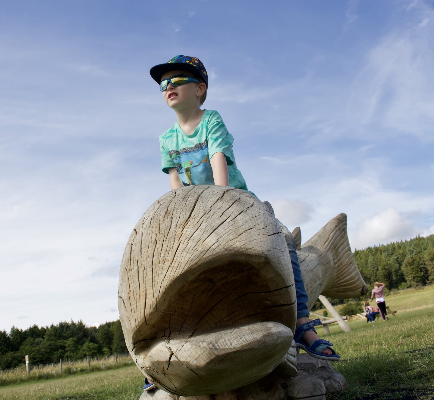 A young boy climbing on a wooden fish