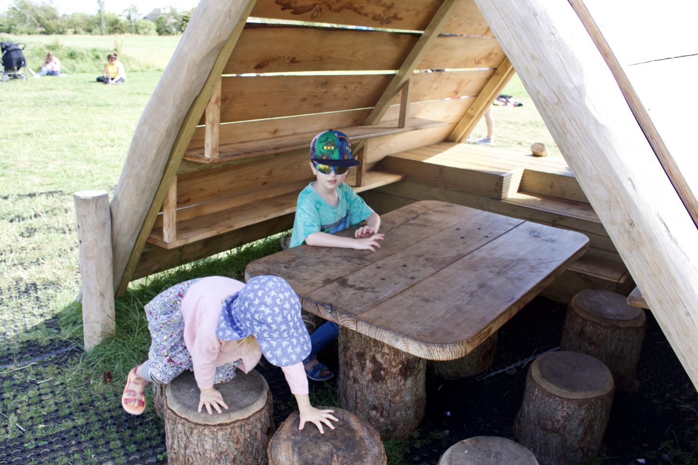 Two children playing at a wooden table and stools 