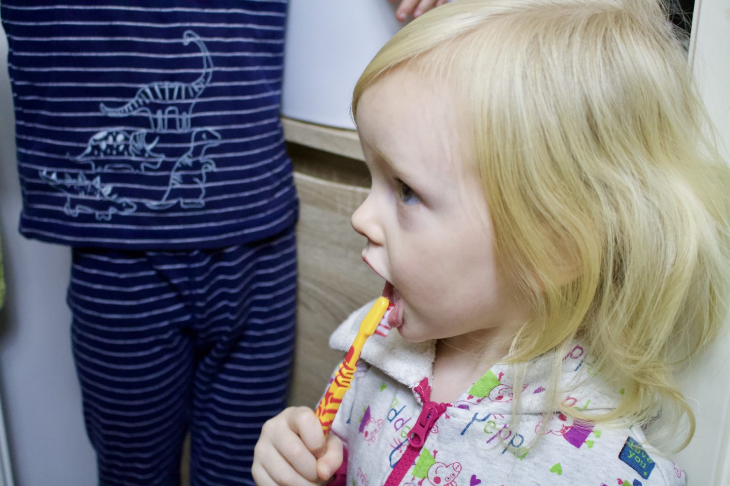 Blonde toddler brushing her teeth