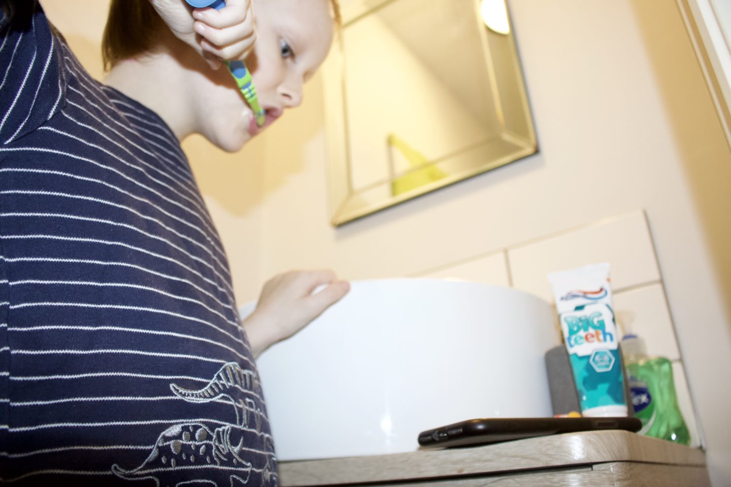 Little boy brushes his teeth whilst using a toothbrushing app