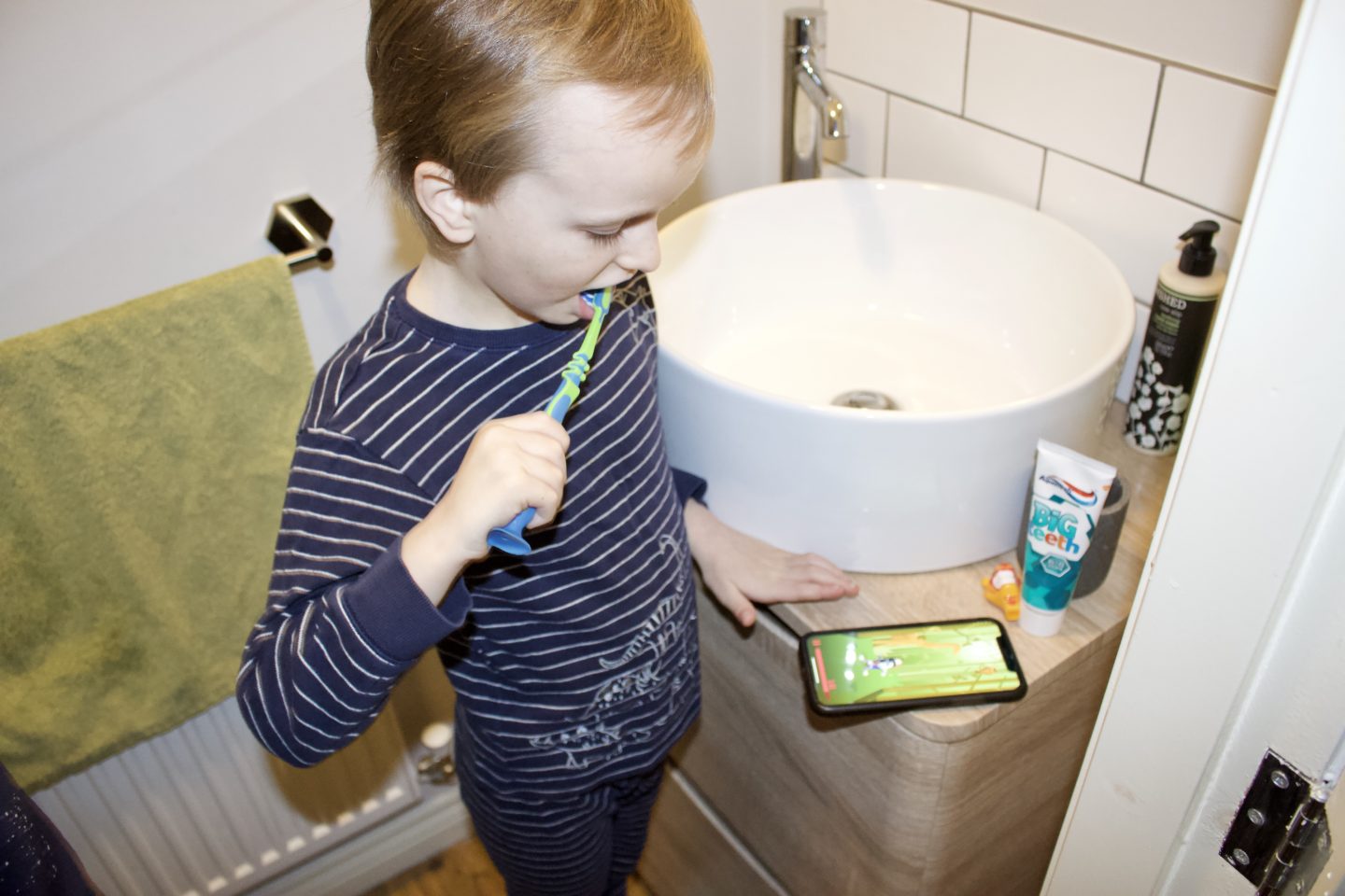 Little boy brushes his teeth whilst using a toothbrushing app