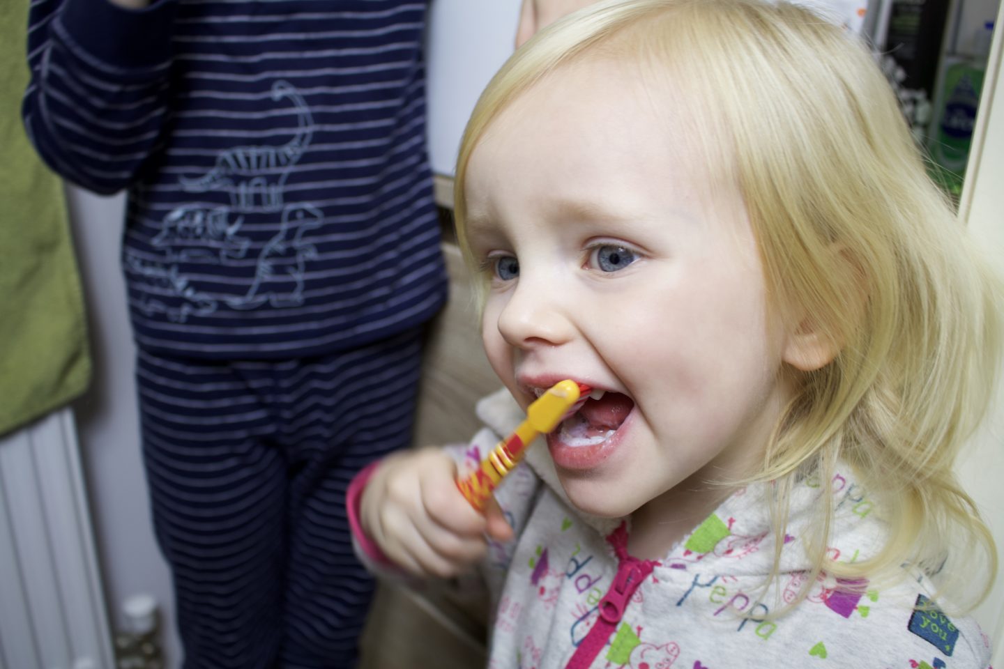 Blonde toddler concentrating whilst brushing her teeth