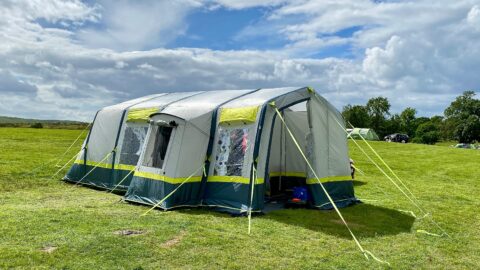 The OLPRO Home 5 berth family tent which is large, light grey, blue and neon green accents in a field.