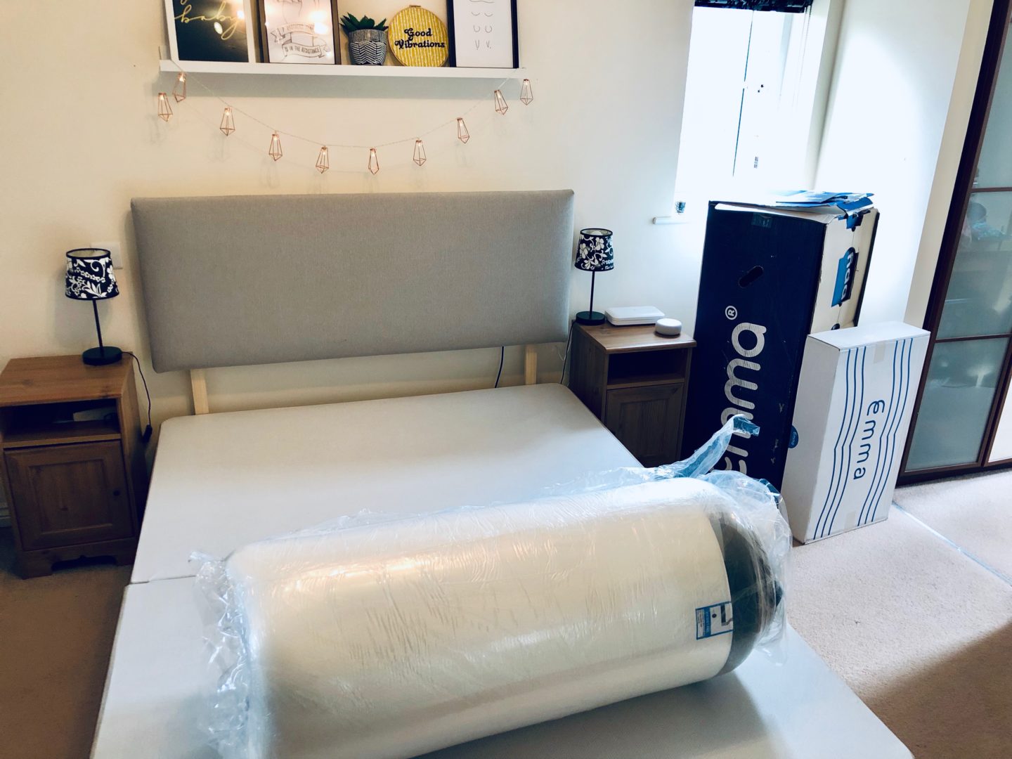 A bed with the Emma Mattress taken out of its box but still in its plastic wrapping. 