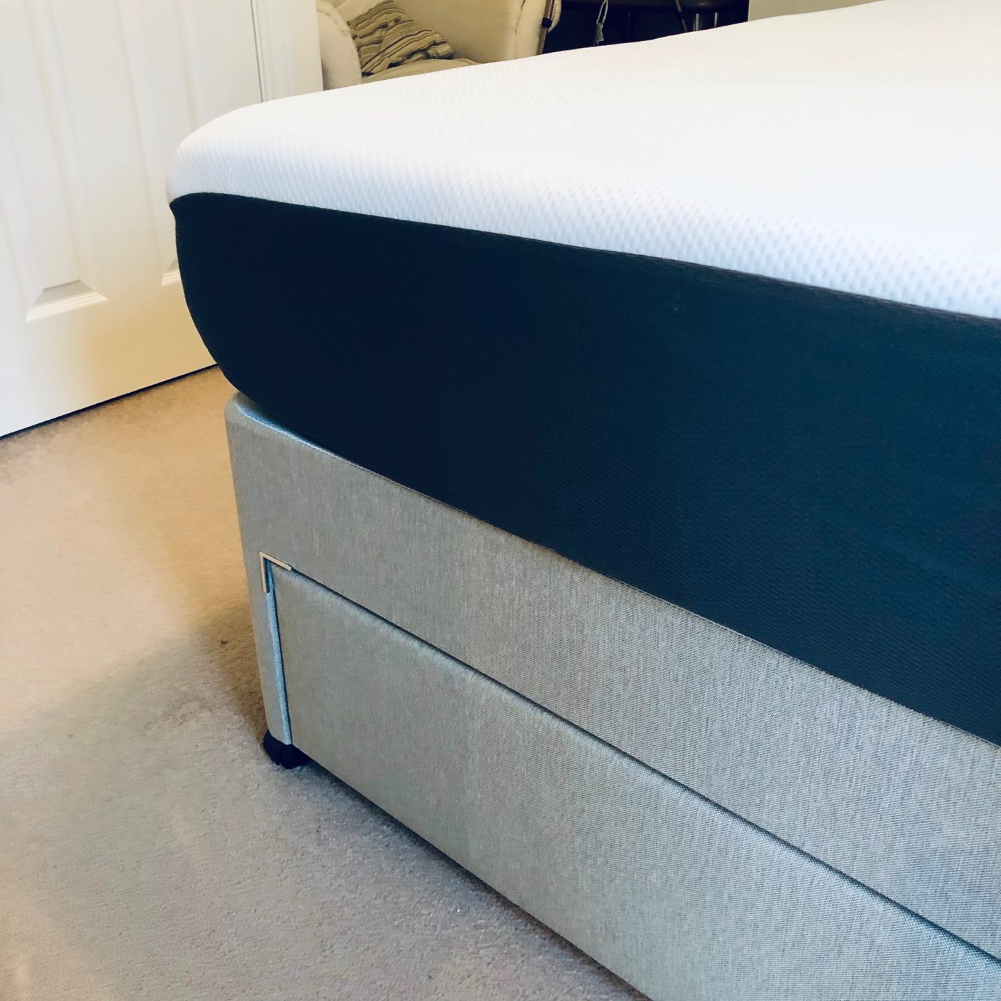 The Emma Mattress with the mattress protector on it on a grey base bed 